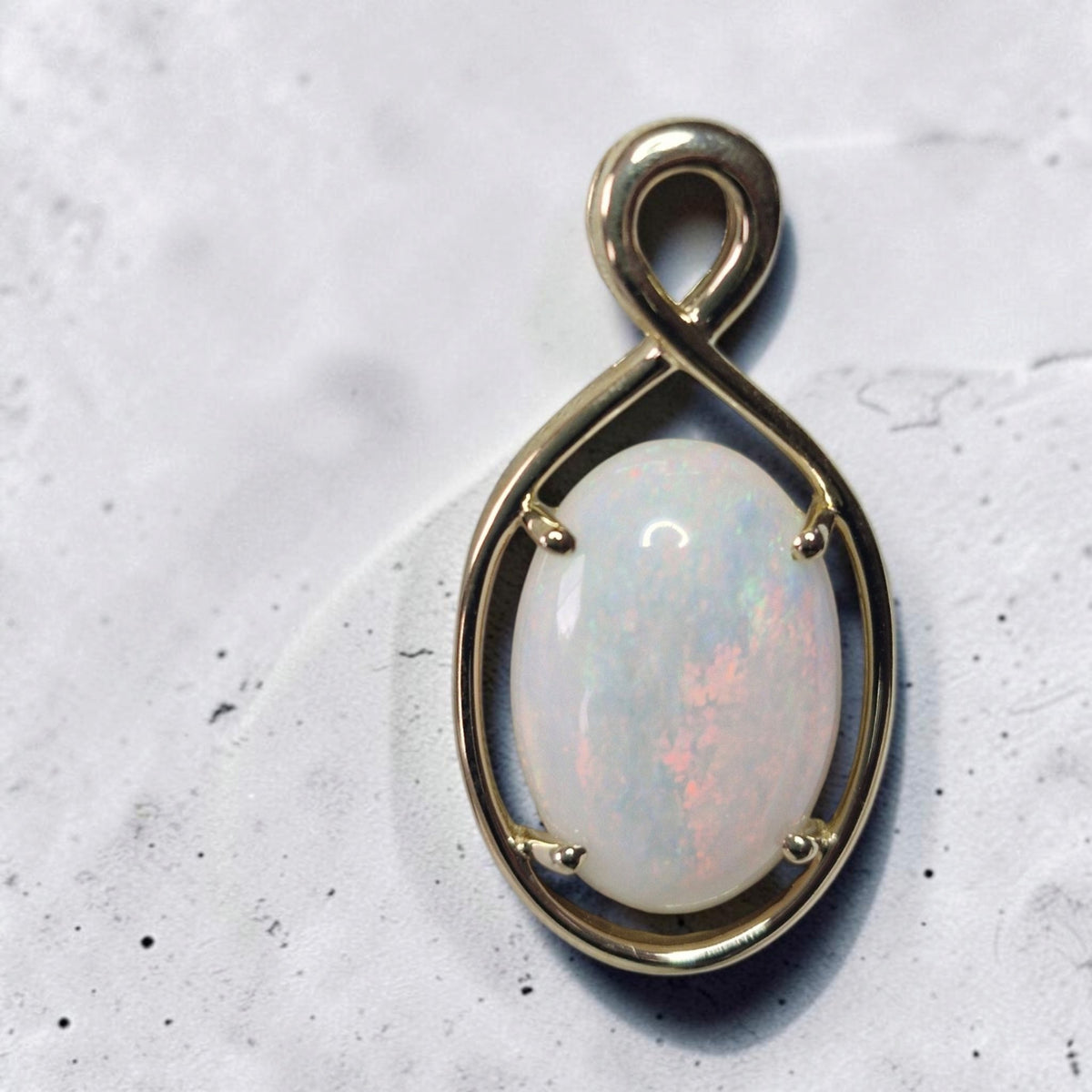 Time & Lustre oval opal pendant featuring a cabochon gemstone in a polished gold infinity-inspired four-prong setting.