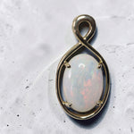 Time & Lustre oval opal pendant featuring a cabochon gemstone in a polished gold infinity-inspired four-prong setting.