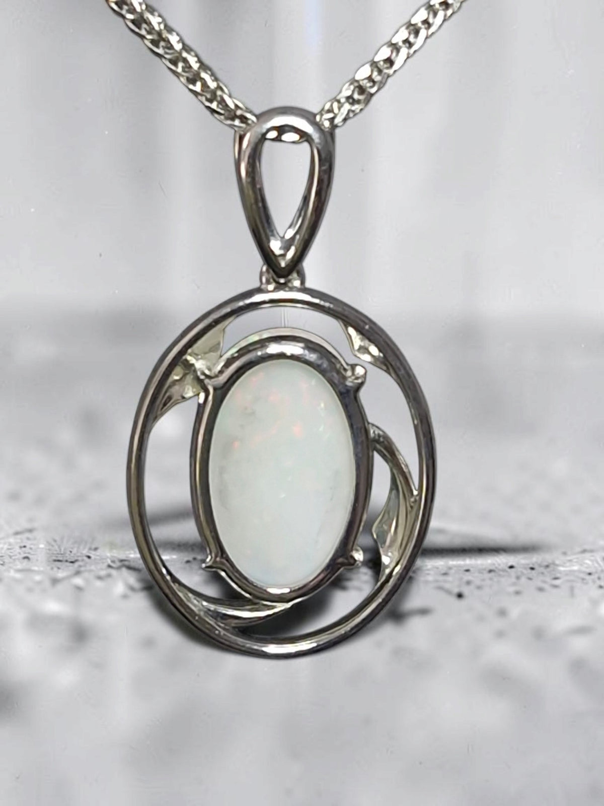 Time & Lustre oval opal pendant featuring an iridescent gemstone in a polished silver-toned organic frame on a chain.