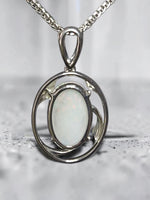 Time & Lustre oval opal pendant featuring an iridescent gemstone in a polished silver-toned organic frame on a chain.