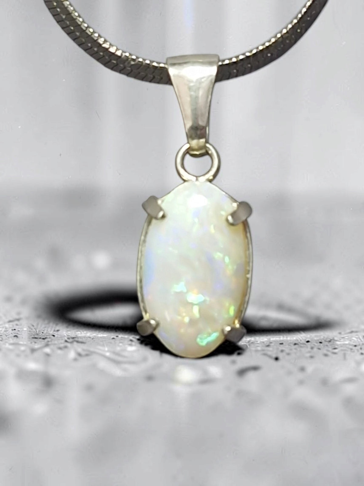 Time & Lustre oval opal pendant in 925 sterling silver with a four-prong setting showing iridescent colour flashes.