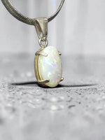 Time & Lustre oval opal pendant in 925 sterling silver with a four-prong setting and iridescent colour flashes.