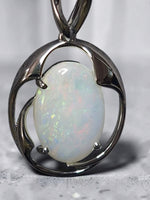 Time & Lustre oval opal pendant featuring a luminous gemstone with iridescent flashes in a polished silver-tone frame.