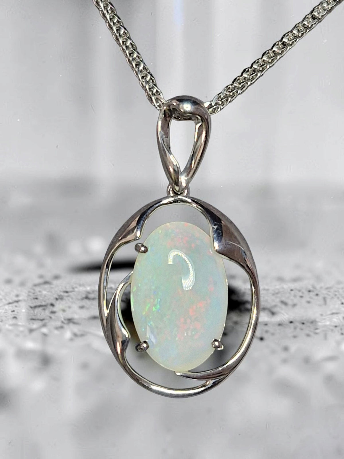 Time & Lustre oval opal pendant featuring a luminous gemstone in a polished silver-toned organic frame on a chain.