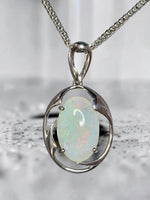 Time & Lustre oval opal pendant featuring a luminous gemstone in a polished silver-toned organic frame on a chain.
