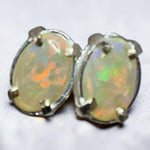 Time & Lustre oval opal stud earrings featuring vibrant green and orange fire in a classic four-prong metal setting.