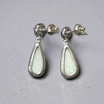 Time & Lustre teardrop opal drop earrings in polished sterling silver with post-back closures on a grey surface.